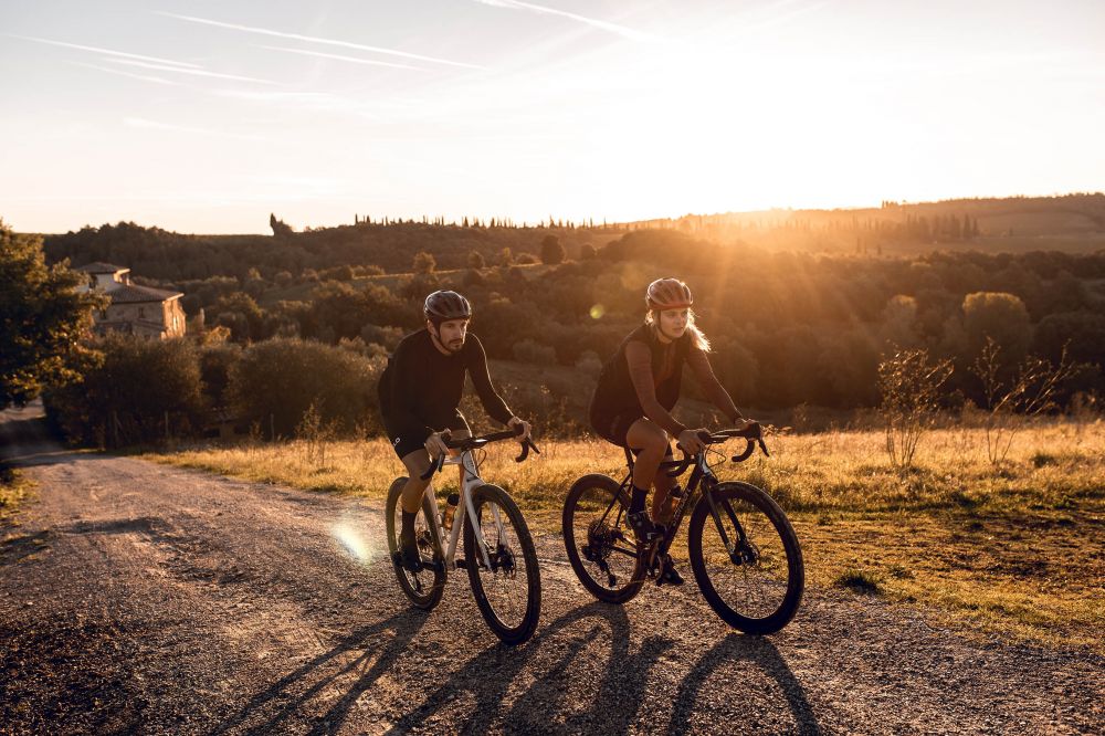 Ein Mann und eine Frau fahren bei Sonnenuntergang mit ihren Rädern einen Hügel bergauf